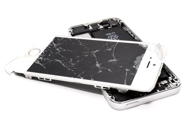 A cracked, shattered phone lies on a white background.